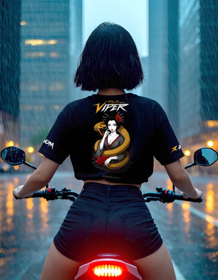 Woman on a motorcycle in the rain wearing a black anime t-shirt with a bold Geisha and snake design on the back. The shirt features Japanese streetwear aesthetics and eco-friendly, high-quality branding in a dynamic urban setting.